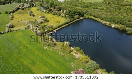 Aerial view of green fields and trees with a lake also in view. Aerial drone photo. Taken in Lancashire England.