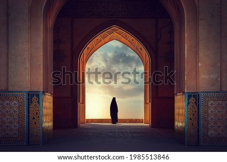 Silhouette of a Persian woman in national dress against the background of traditional Iranian architecture. Sunset. Iran. Kashan. Royalty-Free Stock Photo #1985513846