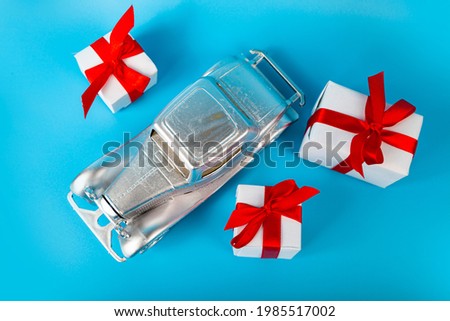 Silver car with gifts on a blue background. Buying a car.