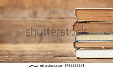 Back to school and education concept. The stack of books on the wooden background and place for text.