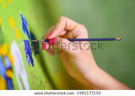 Close-up Shot of Female Artist Hand, Holding Paint Brush and Drawing Oil Painting. Contemporary Painter Creating Modern Abstract Piece of Fine Art. High quality photo