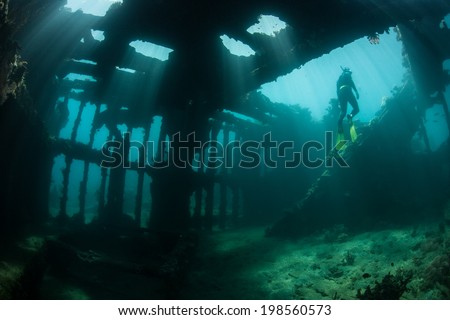 Brilliant beams of sunlight illuminate the remains of a shipwreck in the Solomon Islands. Many ships were sunk in this area during World War II. The wrecks now make artificial reefs. Royalty-Free Stock Photo #198560573