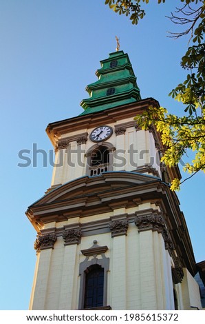 Detailed view the tower with the clock of the Cathedral of the Immaculate Conception of the Blessed Virgin Mary in Ternopil, Ukraine. Blus sky background. Tree leaves border.