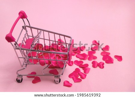 Valentine's day, endless love or special occasion concept. Top view of red hearts spilled out of a shopping cart. isolated on pink background. copy space.