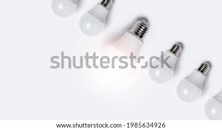 Close-up of light bulbs with one glowing against white background. 