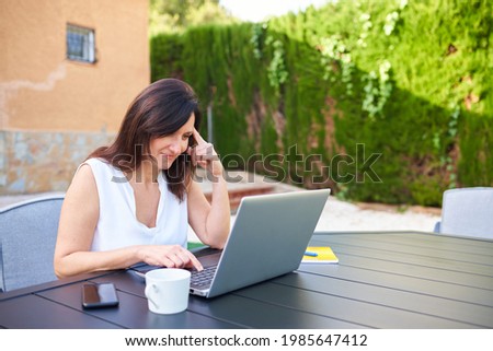 Business woman telecommuting with her laptop outdoors from her home garden