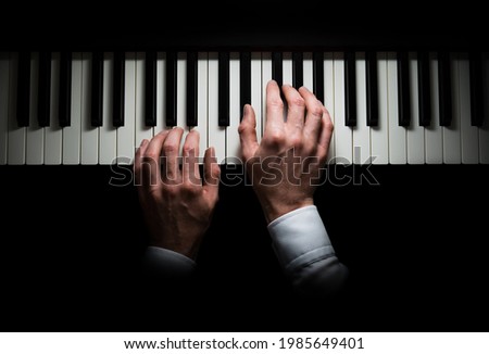 Isolated hands playing on the piano, dark background Royalty-Free Stock Photo #1985649401