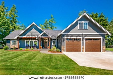 Craftsman home with double garage lush green lawn and blue sky Royalty-Free Stock Photo #1985658890