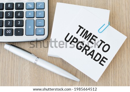 Text time to upgrade on the short note texture background on a wooden background near calculator and pen
