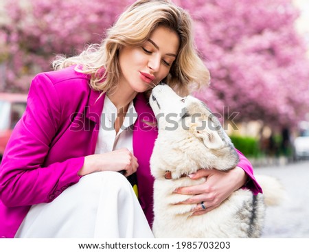 Kiss. Beautiful young woman playing with her little west highland white terrier in a park outdoors. Lifestyle portrait. Beauty woman with her dog playing outdoors. Love and kis pet