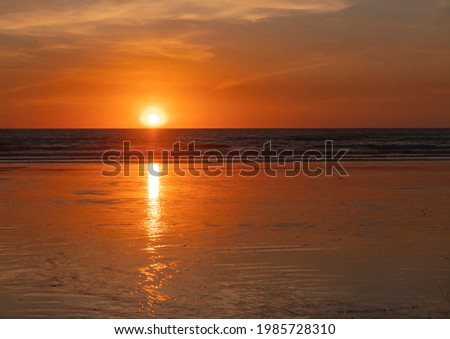 Sunset over Cable Beach in Broome Western Australia with orange sky, sun, and wet sandy beach. Royalty-Free Stock Photo #1985728310