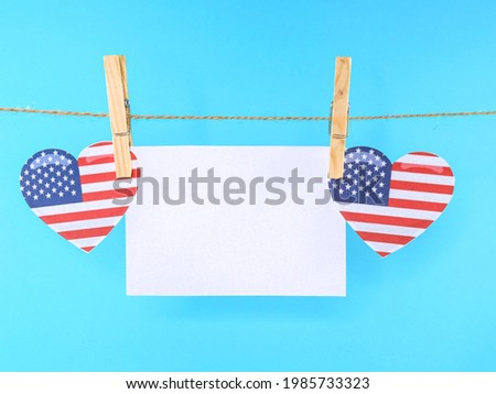 
Hearts with the American flag hanging from a clothesline.
Hearts with American flag and blank sheet hanging on a clothesline, close-up side view.