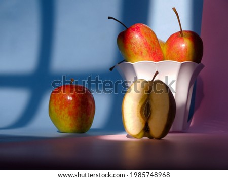 Photo of an apple in a container on a pink and blue background
