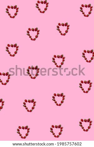 Pattern of strawberries in the shape of hearts on a pink background.