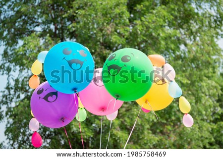 Colored balloons with smiles on the background of trees.