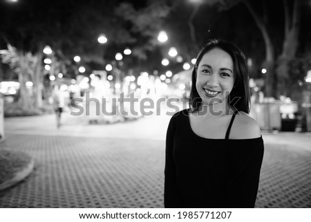 Portrait of young beautiful Filipina woman relaxing at the night market in black and white