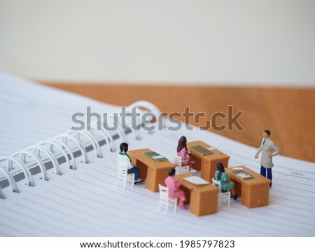 Miniature people toys on the paper book with blurred wooden table. Education and school concept. Royalty-Free Stock Photo #1985797823