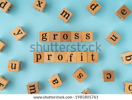 Gross Profit word on wooden block. Flat lay view on blue background.