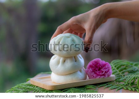 Steamed bun overlap take my lady hand  on wood tray fern flower .closeup