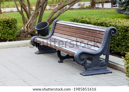Photo of a bench on the street in the city in summer against the backdrop of greenery park. High resolution picture