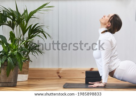 closed plane of woman stretching on a yoga mat with plants and beautiful surroundings.