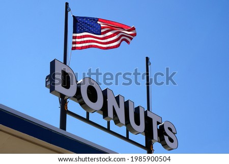 A picture of an iron sign that reads "DONUTS" and above it the flag of the United States of America.
