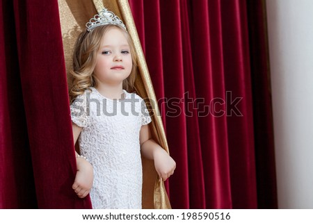 Image of lovely little girl looking out curtains