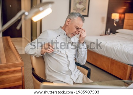 Gray-haired man feeling tired after a long working day