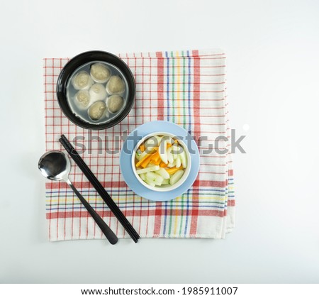 Pickled cucumber and carrots and meatballs on napkin mat on white background.