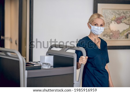 Service woman in a protective mask sholding bottles with water