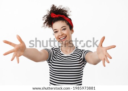 Portrait of friendly pretty girl stretching arms, welcome and hugging you, smiling happy, loves to cuddle, standing against white background
