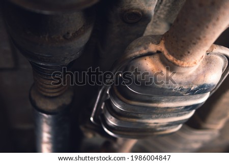 Vehicle underbody exhaust pipe, catalyst, resonator, exhaust system. Old parts require repair and replacement. Car service and maintenance. Standards and technical condition. selective focus Royalty-Free Stock Photo #1986004847