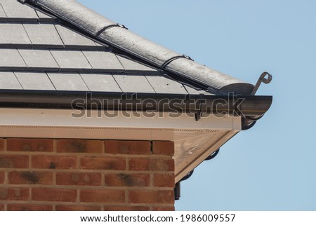 New build property showing detail of mortar free ridge tiles, plastic fascias, soffits and guttering. Royalty-Free Stock Photo #1986009557