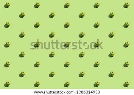 Minimal repetitive pattern made of green appes on green background