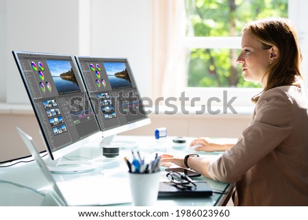 Young Female Editor Editing Video On Computer In Office