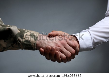 Soldier and businessman shaking hands against grey background, closeup