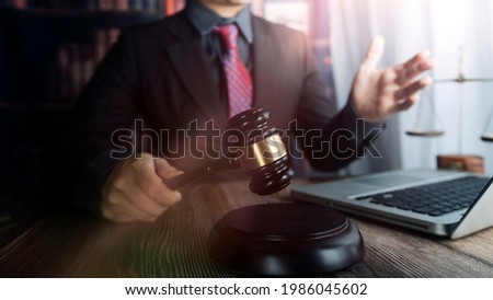 Justice and law concept.Male judge in a courtroom with the gavel, working with, computer and docking keyboard, eyeglasses, on table in morning light
