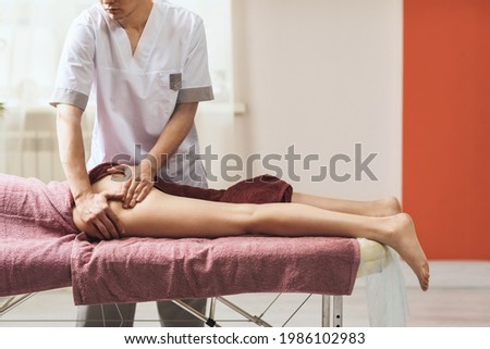 A man performing a massage on the thigh and gluteal muscles in his office. Royalty-Free Stock Photo #1986102983