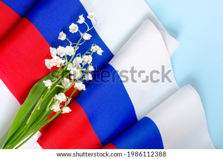 June 12 - Independence Day of Russia. February 23 Defender of the Fatherland Day. A bouquet of lilies of the valley against the background of the Russian flag. Scarf in the colors of the Russian flag.