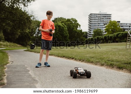 teen boy with electric remote control car toy play outdoor on sidewalk and have fun while enjoy his childhood Royalty-Free Stock Photo #1986119699