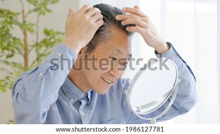 Asian senior man checking hair Royalty-Free Stock Photo #1986127781