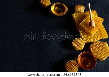 Honey with honeycomb on black table, top view. space for text.