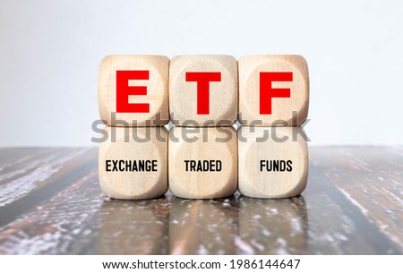ETF, Exchange Traded Fund, realtime mutual index fund that can trade in equity stock market, cube wooden block with alphabet building the word ETF on grid line paper, random block in the background. Royalty-Free Stock Photo #1986144647