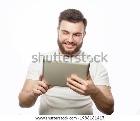 Tehnology, people and lifestyle concept: young bearded man wearing white t-shirt using a tablet computer - isolated over a white background