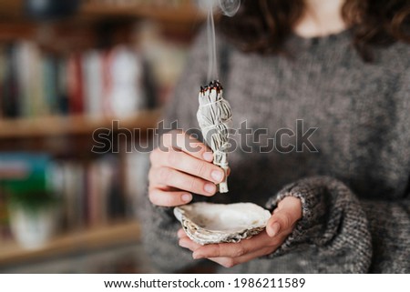 Woman burning sage smudge to cleanse the house Royalty-Free Stock Photo #1986211589