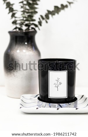 Black candle mockup by a vase