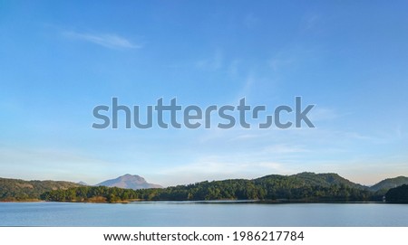 Calm lake water with mountains and blue skies in the background.