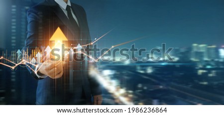 Businessman holding arrow up and analysis economic with graph of business growth, Business development to success and growth, finance and banking, marketing, strategy and planning to corporate. Royalty-Free Stock Photo #1986236864