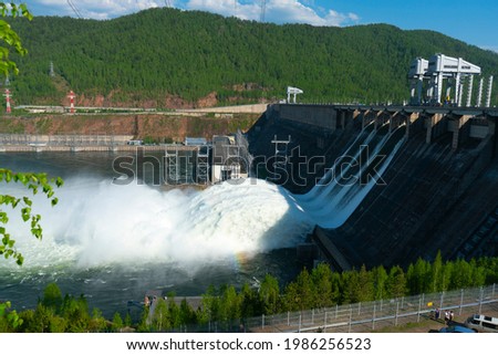 Discharge of water at a hydroelectric power plant. Hydroelectric power station in a mountainous area. Discharge of excess water from three locks. Royalty-Free Stock Photo #1986256523