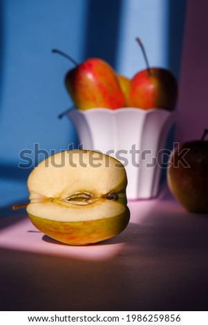 Photo of an apple in a container on a pink and blue background